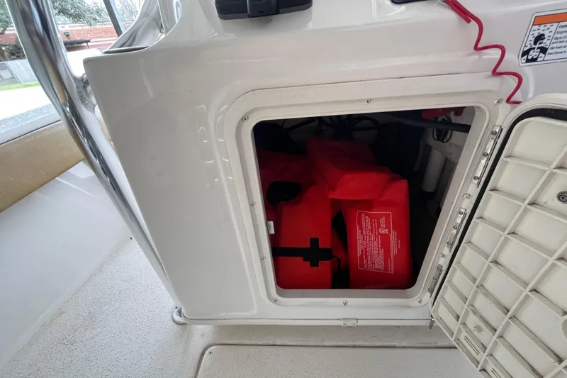 Slide: The Image of 2024 Sea Chaser 21 LX boat storage compartment with red life jackets inside. - 18