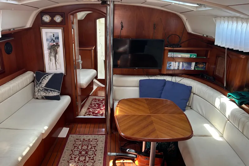 Slide: The Image of Interior of 2000 Beneteau Oceanis Clipper 411 yacht with cozy seating and wooden table. - 12