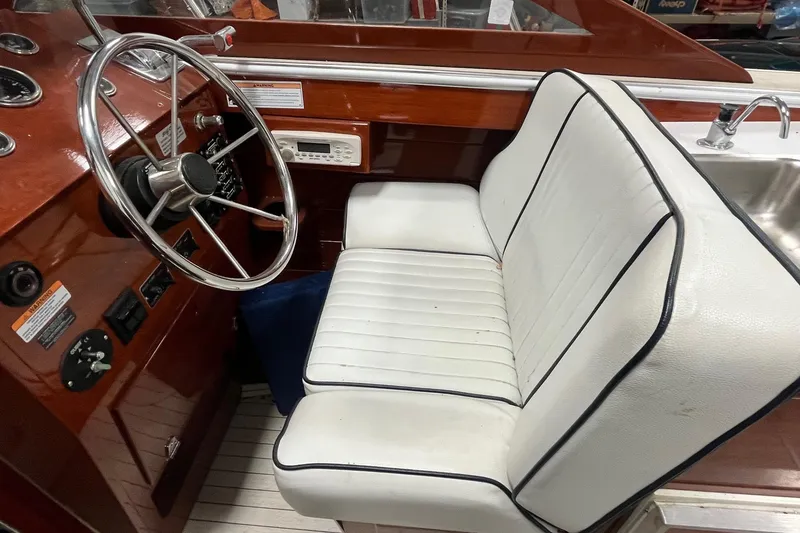 Slide: The Image of Interior of a 2006 Skiff Craft 24' Runabout with white seating and wooden dashboard. - 18