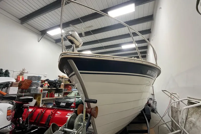 Slide: The Image of 2006 Skiff Craft 24' Runabout boat stored indoors, surrounded by various items. - 3