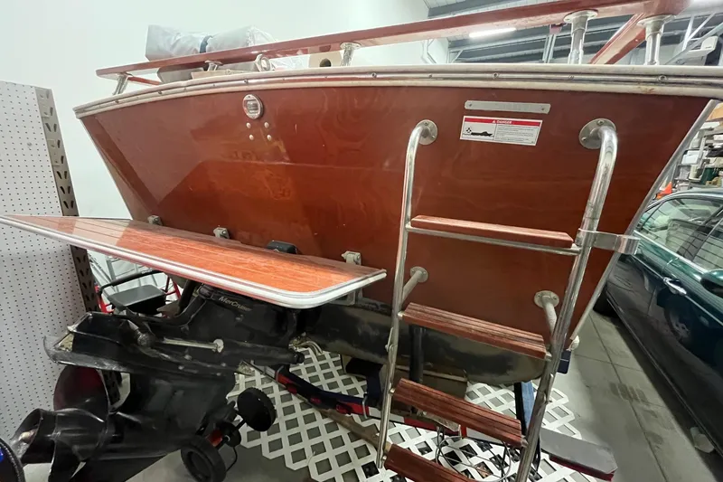 Slide: The Image of 2006 Skiff Craft 24' Runabout boat with wooden finish and metal ladder in a garage. - 8