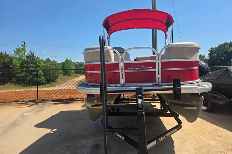 Slide: The Image of 2017 Sun Tracker Party Barge 18 DLX pontoon boat on trailer, red canopy, outdoor setting. - 5