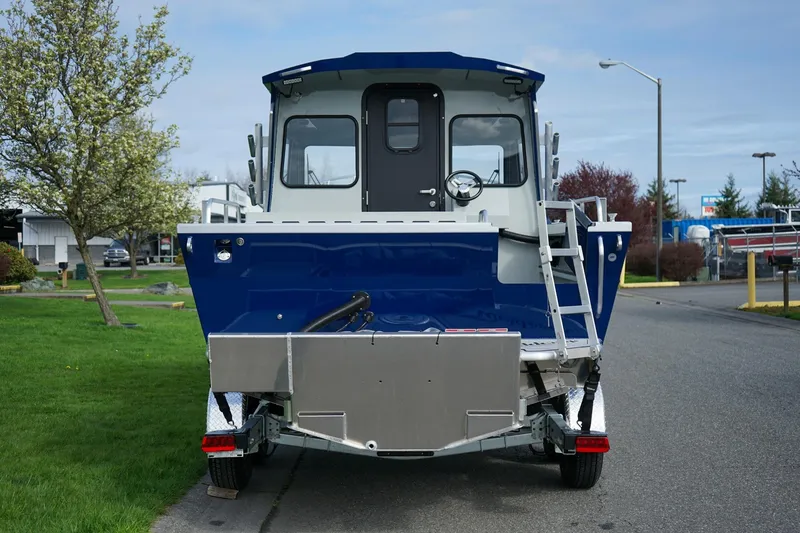 Slide: The Image of 2026 Weldcraft 220 Ocean King boat, rear view, parked on a street with green grass and trees. - 4