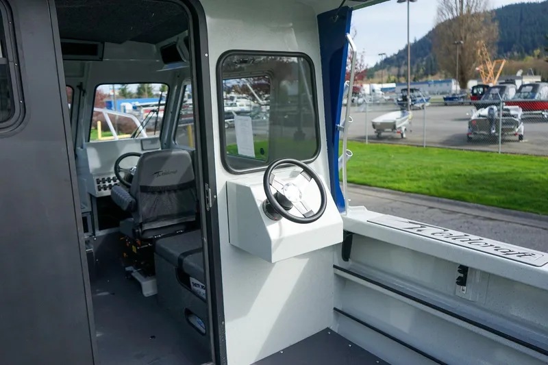 Slide: The Image of 2026 Weldcraft 220 Ocean King boat interior with steering wheel and seating, parked outdoors. - 8