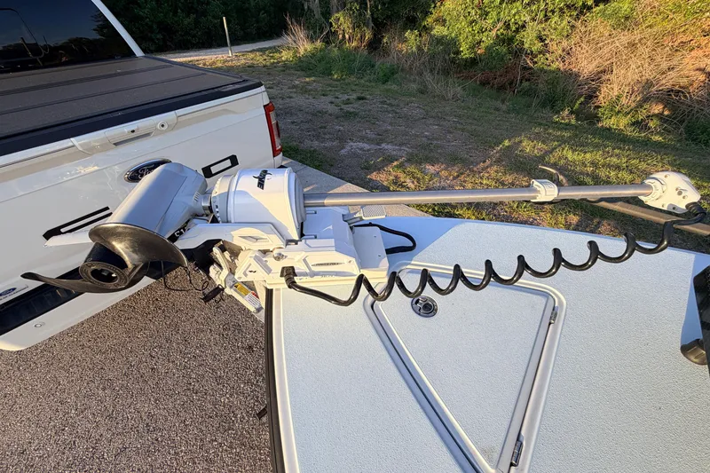 Slide: The Image of 2025 Chittum Skiffs Islamorada 21 with motor, parked near a white truck. - 21