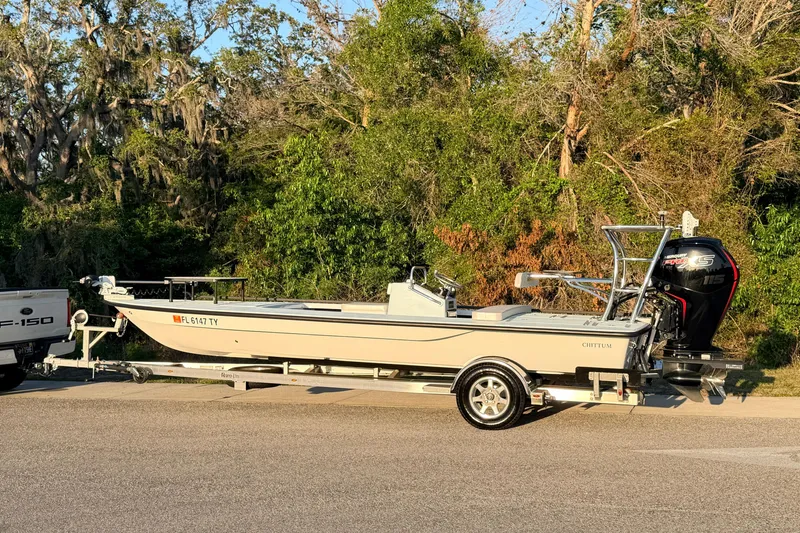 Slide: The Image of 2025 Chittum Skiffs Islamorada 21 boat on trailer, parked near lush greenery. - 3
