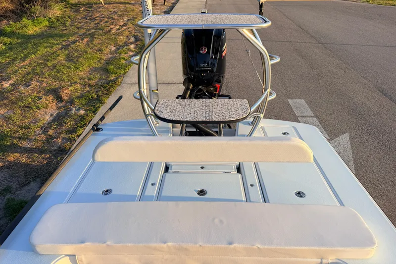 Slide: The Image of 2025 Chittum Skiffs Islamorada 21 boat with cushioned seating and motor, parked on roadside. - 56