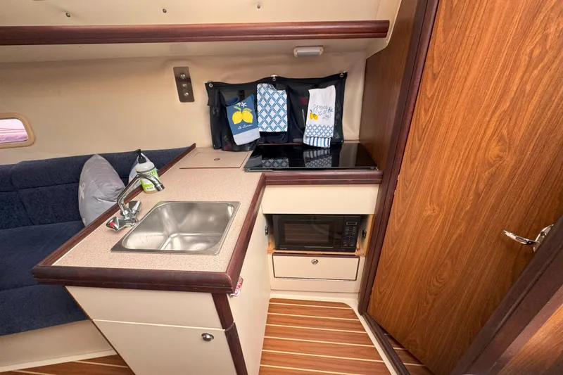 Slide: The Image of Compact kitchen area in a 2007 Hunter 27 sailboat with sink, stove, and microwave. - 27