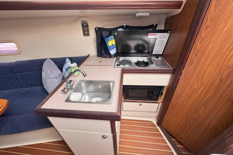 Slide: The Image of Compact kitchen area in a 2007 Hunter 27 sailboat with sink, stove, and microwave. - 28
