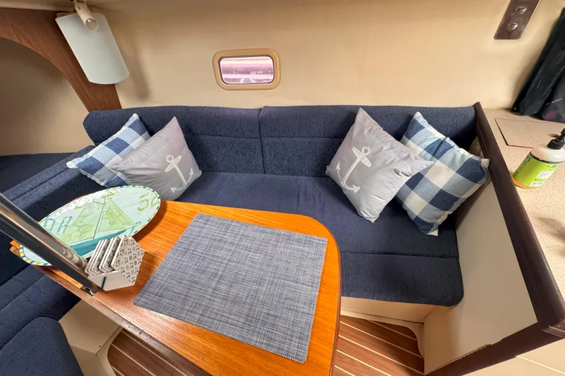 Slide: The Image of Interior of a 2007 Hunter 27 sailboat with blue seating and nautical-themed pillows. - 31