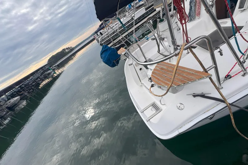 Slide: The Image of Sailboat docked at marina, Hunter 27 model, 2007, reflecting on calm water under cloudy sky. - 4