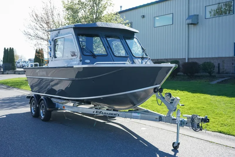 The Image of 2026 Weldcraft 210 Revolution boat on trailer, parked outdoors near industrial building. - 1