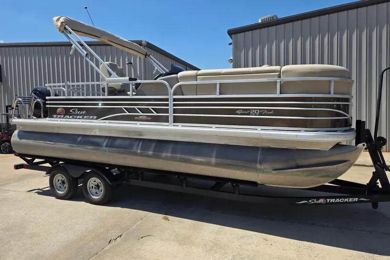 The Image of 2023 Sun Tracker SportFish 20 DLX pontoon boat on trailer, parked outdoors. - 0