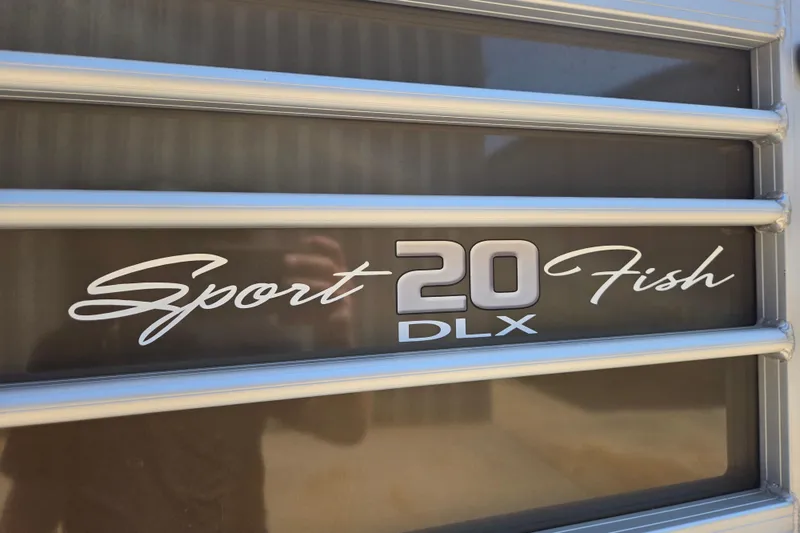 Slide: The Image of 2023 Sun Tracker SportFish 20 DLX logo on a sleek metallic surface. - 5