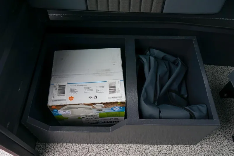 Slide: The Image of Storage compartments in a 2026 Alumaweld Intruder Outboard 22 boat, containing a box and fabric. - 16