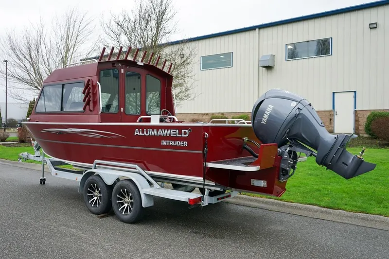 Slide: The Image of 2026 Alumaweld Intruder Outboard 22 boat on trailer, red exterior, parked outdoors. - 4