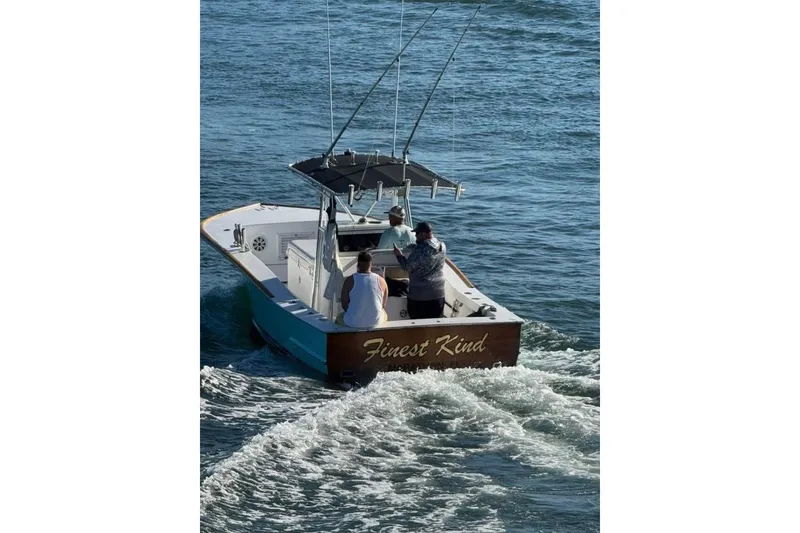 Slide: The Image of 1977 Scarborough 27 CC boat interior at marina, featuring white seating and wooden trim. - 15