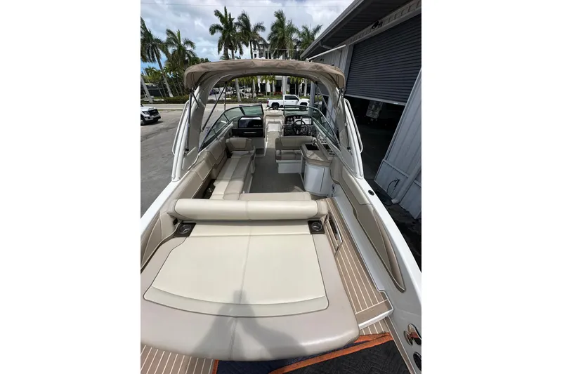 Slide: The Image of 2018 Formula 290 Bowrider boat interior with seating and canopy, docked near palm trees. - 9
