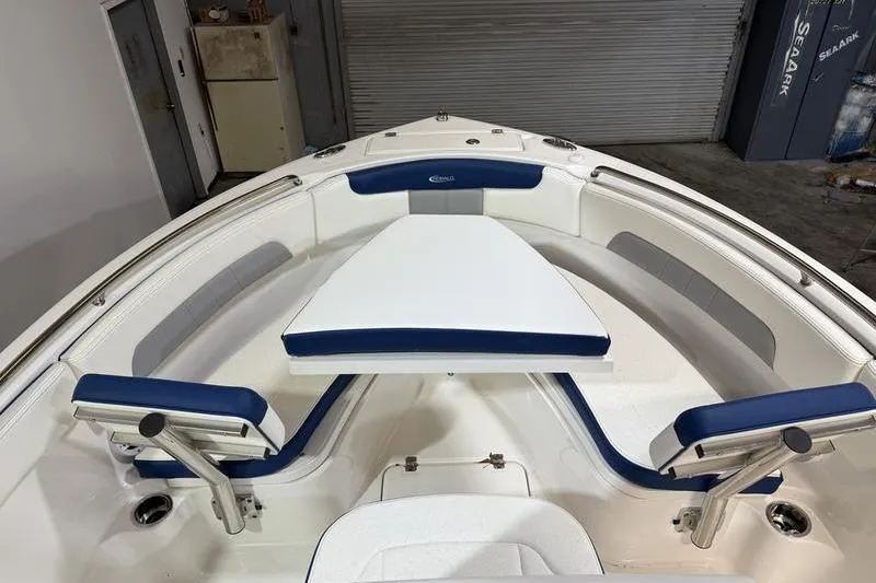 Slide: The Image of 2026 Robalo R222 Explorer boat interior with blue and white seating in a garage setting. - 22