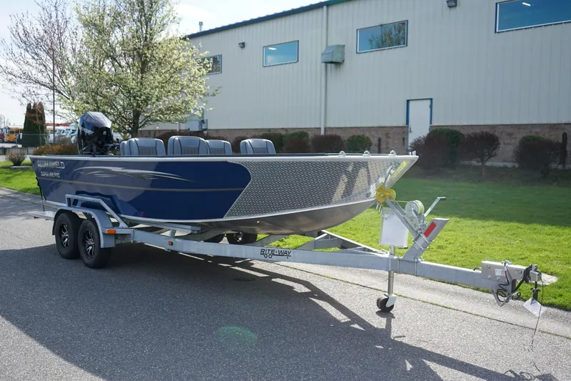 Slide: The Image of 2026 Alumaweld Super Vee Pro 21 boat on trailer, parked outdoors near a building. - 2