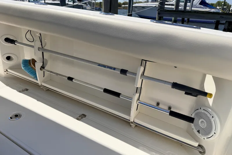 Slide: The Image of 2022 Boston Whaler 250 Outrage boat storage compartment with cleaning tools and speaker. - 21