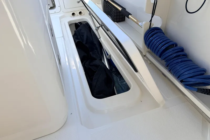 Slide: The Image of 2022 Boston Whaler 250 Outrage storage compartment with coiled blue hose and equipment. - 24
