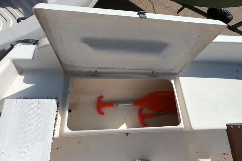 Slide: The Image of Open storage compartment on a 1978 Newport 16 boat with orange paddles inside. - 8