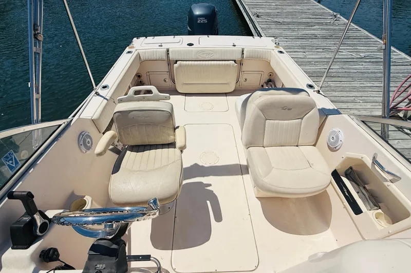 Slide: The Image of 2005 Grady-White Tournament 225 boat interior with seating and steering, docked by the water. - 3