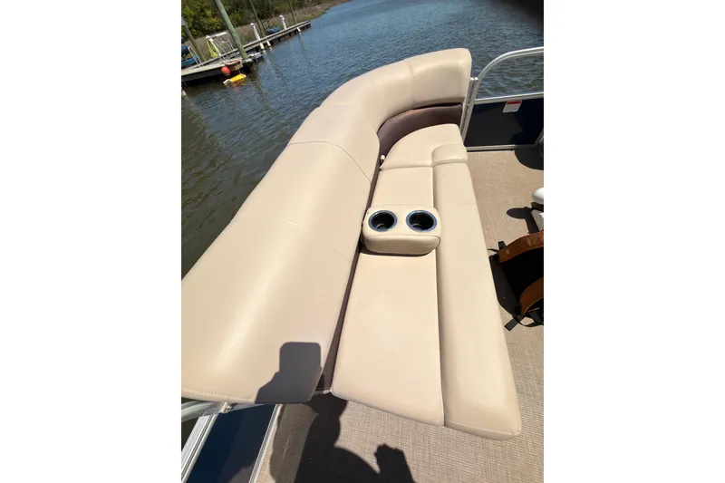 Slide: The Image of 2019 SUNTRACKER Party Barge 20 DLX with beige seating and cup holders on a calm lake. - 12