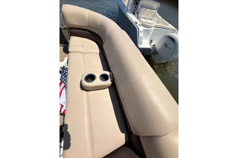 Slide: The Image of 2019 SUNTRACKER Party Barge 20 DLX with beige seating and cup holders on a sunny day. - 13