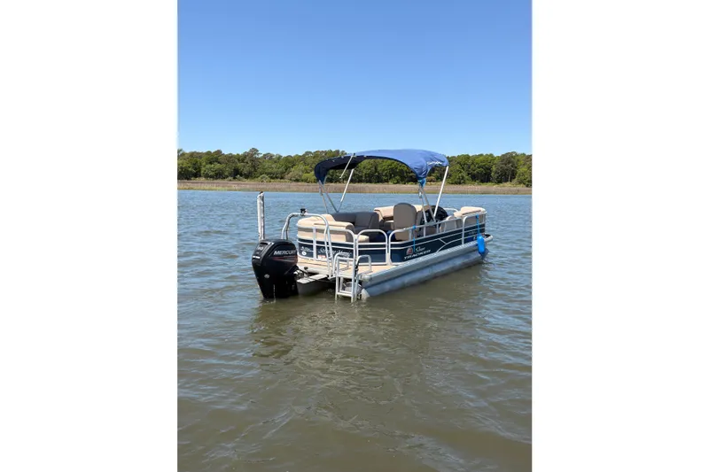 Slide: The Image of 2019 SUNTRACKER Party Barge 20 DLX pontoon boat on calm water with blue canopy. - 2