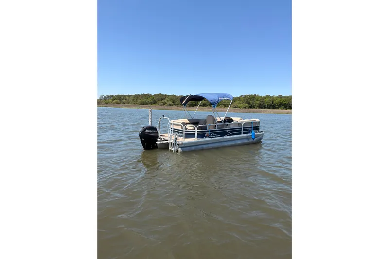Slide: The Image of 2019 SUNTRACKER Party Barge 20 DLX pontoon boat on calm water with blue canopy. - 4