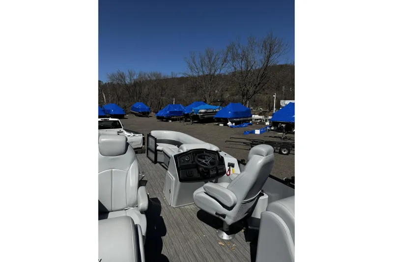 Slide: The Image of 2021 Bentley Pontoons Legacy 243 DL Navigator interior with helm and seating, parked outdoors. - 8