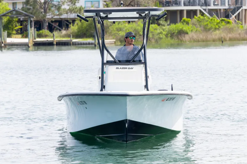 Slide: The Image of 2019 Blazer Bay 2400 boat cruising on calm water near a dock. - 2