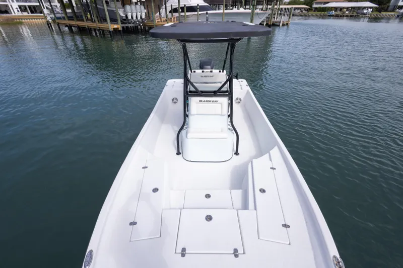 Slide: The Image of 2019 Blazer Bay 2400 boat on calm water, featuring spacious deck and T-top. - 21