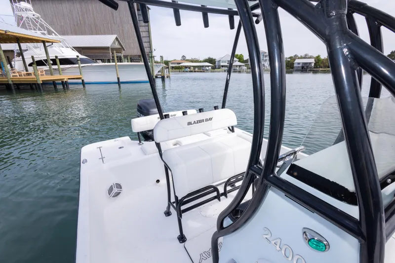 Slide: The Image of 2019 Blazer Bay 2400 boat docked on calm waters near a marina. - 22