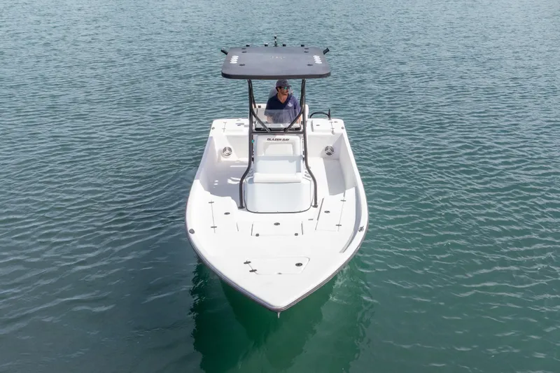 Slide: The Image of 2019 Blazer Bay 2400 boat on calm water, featuring a sleek design and T-top canopy. - 24