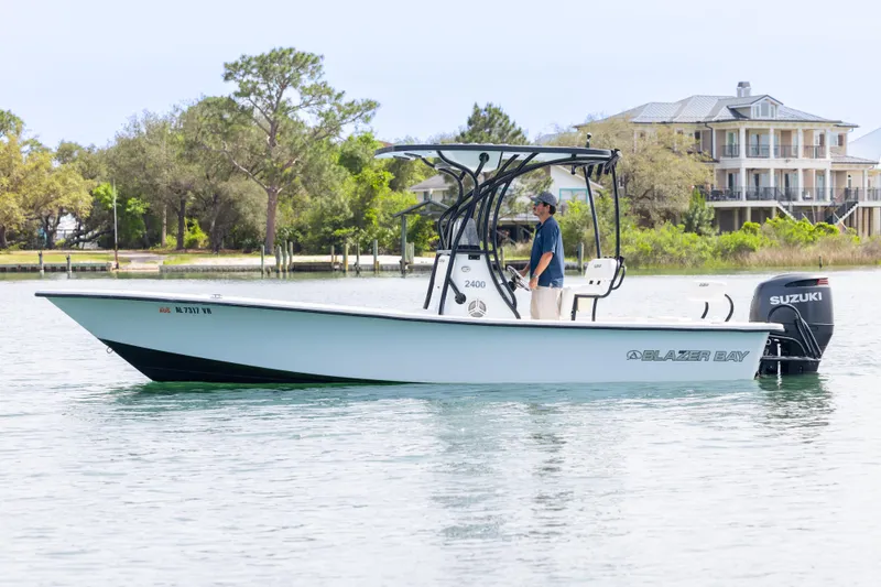 Slide: The Image of 2019 Blazer Bay 2400 boat with Suzuki engine on calm water near shoreline. - 3