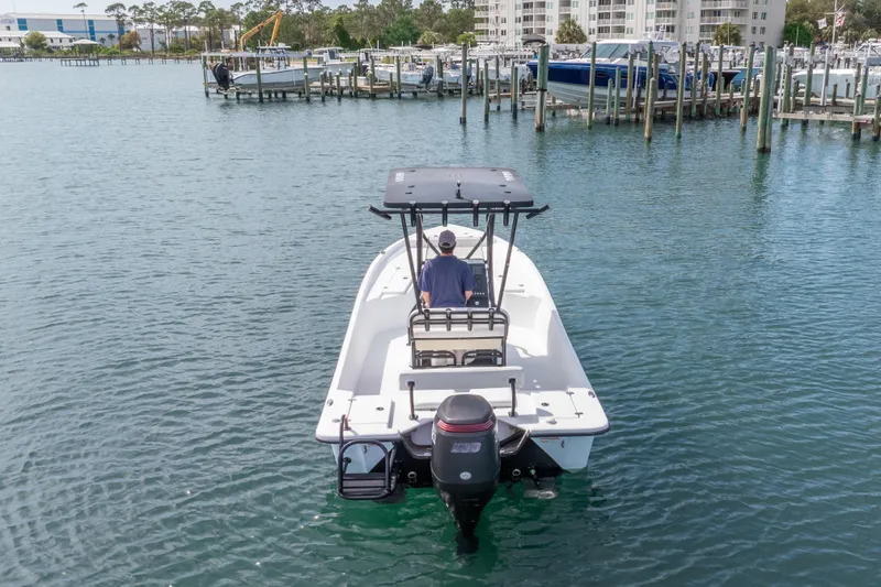 Slide: The Image of 2019 Blazer Bay 2400 boat navigating marina waters, with docks and buildings in the background. - 30