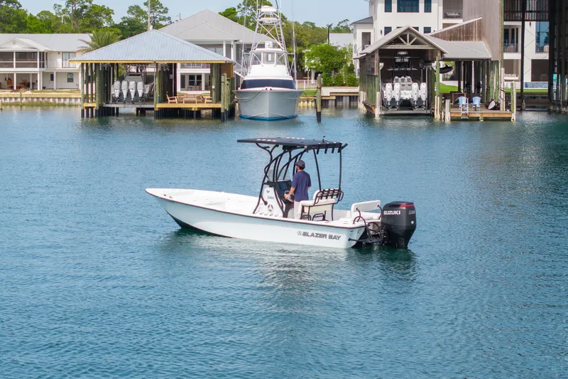 Slide: The Image of 2019 Blazer Bay 2400 boat cruising in a marina with waterfront buildings. - 34