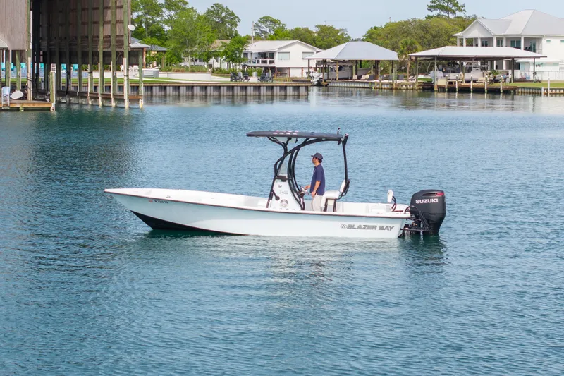 Slide: The Image of 2019 Blazer Bay 2400 boat on calm water near waterfront homes. - 35