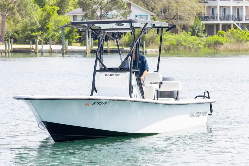 Slide: The Image of 2019 Blazer Bay 2400 boat on calm water near a dock and greenery. - 4