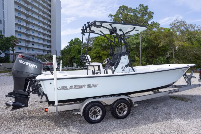 Slide: The Image of 2019 Blazer Bay 2400 boat on trailer with Suzuki outboard motor, parked outdoors. - 9