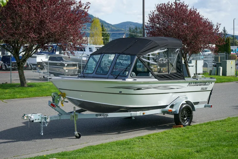 The Image of 2026 Alumaweld Talon 18 boat on trailer, parked near trees and fence. - 0