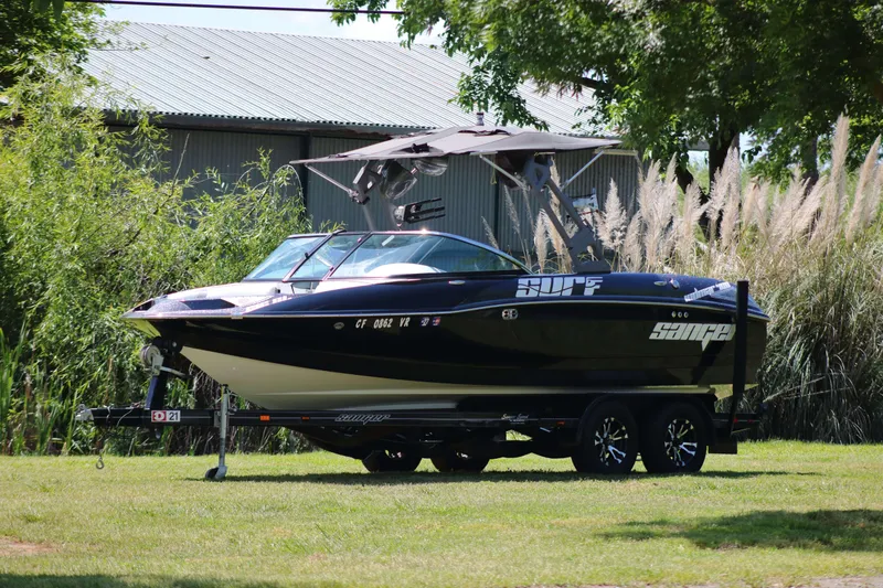 The Image of 2018 Sanger 212 SL boat on trailer, parked on grass near trees and building. - 0