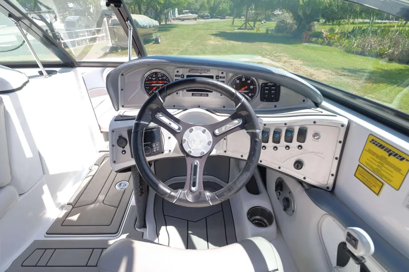 Slide: The Image of Interior of a 2018 Sanger 212 SL boat, featuring a sleek steering wheel and comfortable seating. - 11