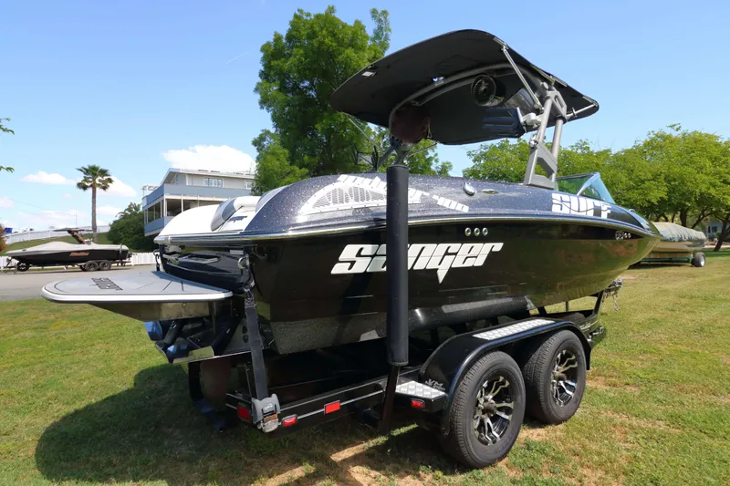Slide: The Image of 2018 Sanger 212 SL boat on trailer, parked on grass with trees in background. - 3
