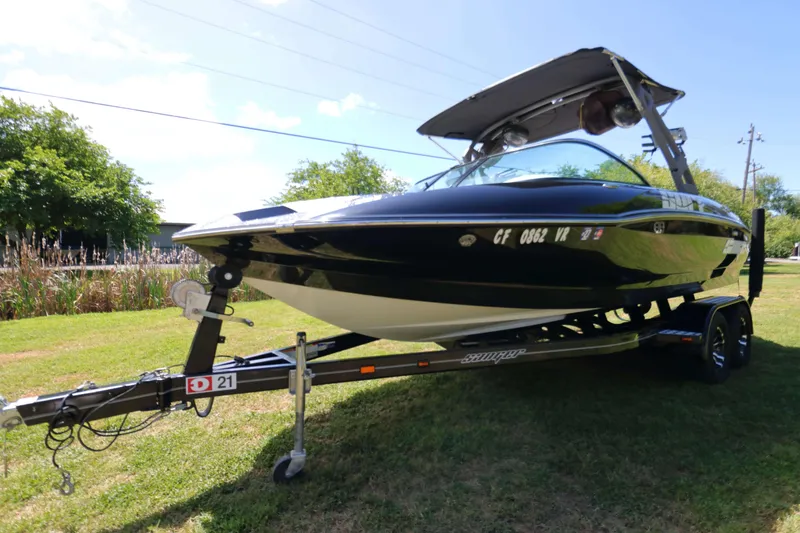 Slide: The Image of 2018 Sanger 212 SL boat on trailer, parked on grass under a clear sky. - 5