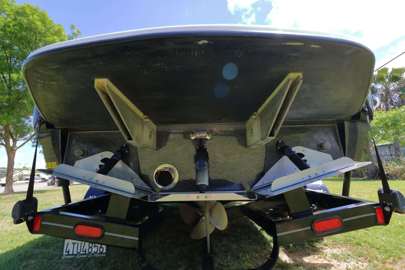 Slide: The Image of 2018 Sanger 212 SL boat interior with seating and speakers, parked on grassy area. - 7