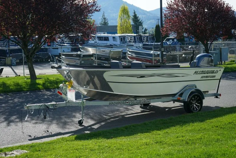 The Image of 2026 Alumaweld Adventurer 20 boat on trailer, parked near marina with scenic background. - 1
